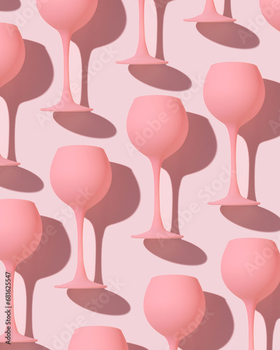 Pink colored wine glasses as trend minimal pattern, monochrome pastel color, romance event or valentine party concept. Creative aesthetic top view of cocktail drink pink background, girly style