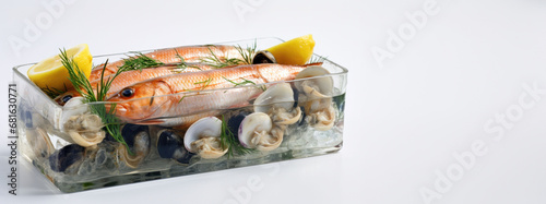 Glass container filled with mussels and a whole fish, accompanied by lemon slices for a refreshing seafood feast.