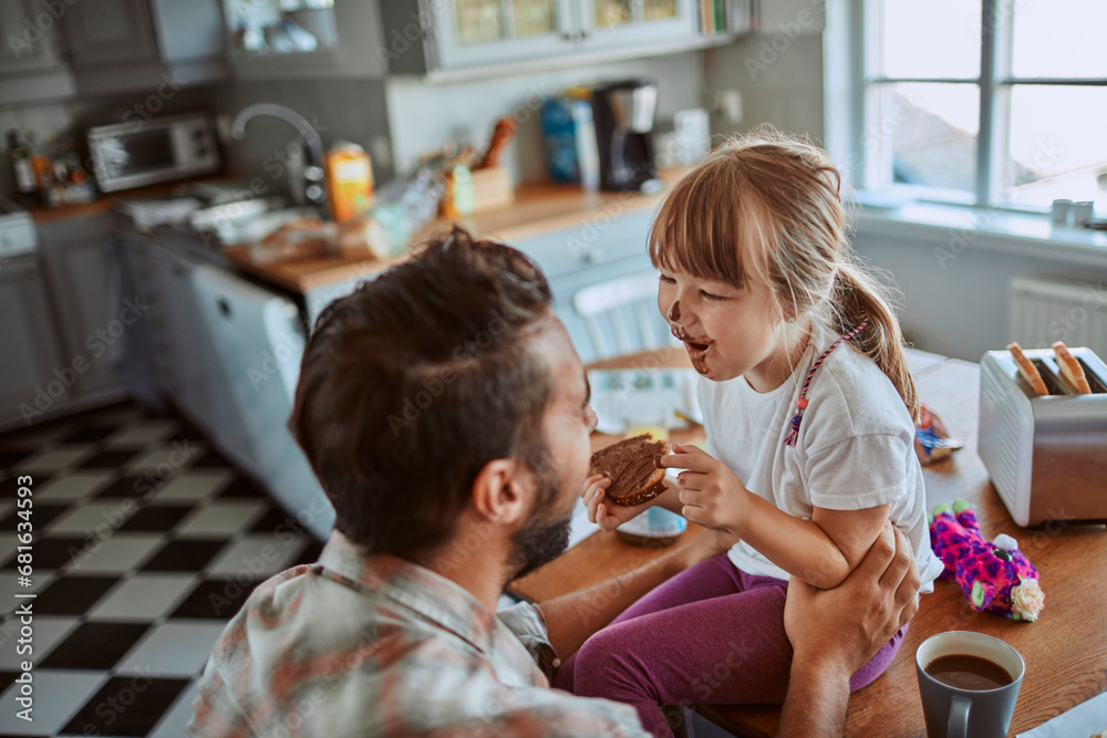 Little girl with messy face playing with father in the kitchen