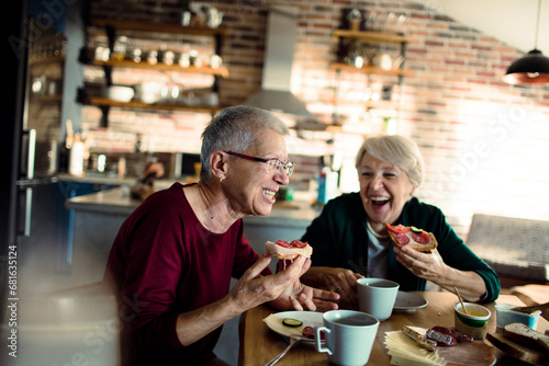 Lifelong senior female friends eating breakfast together at home