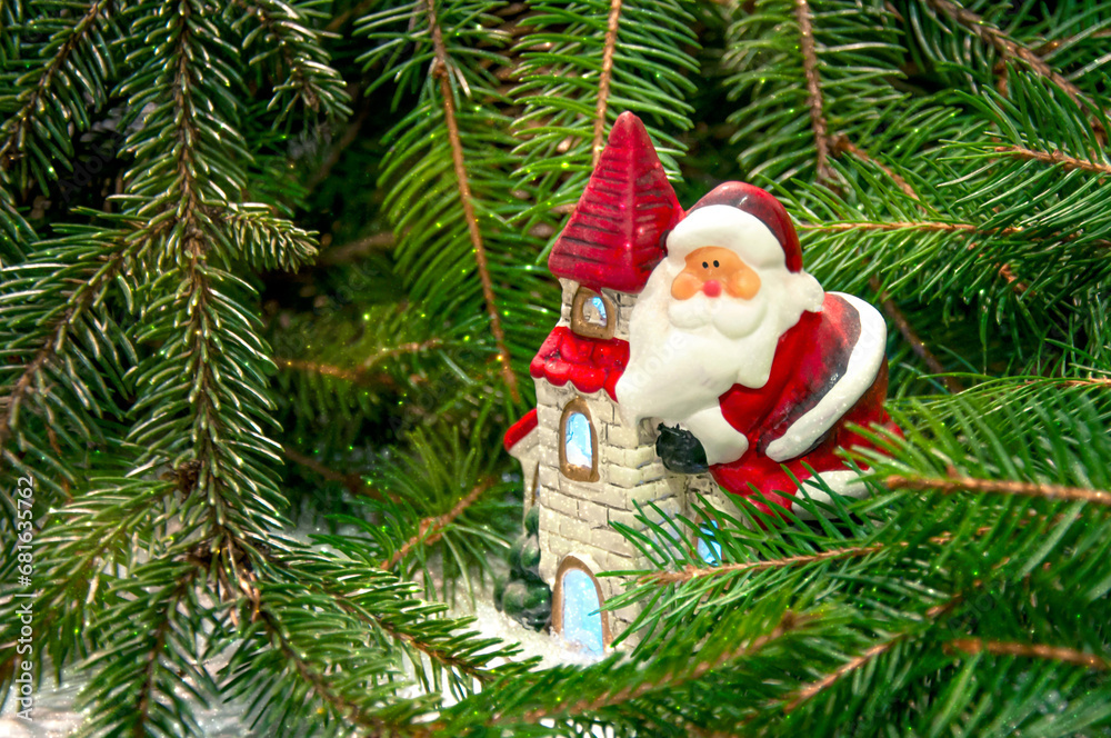 Obraz premium Santa Claus on a house near the branches of a Christmas tree. Background for New Year and Christmas.