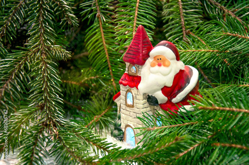 Santa Claus on a house near the branches of a Christmas tree. Background for New Year and Christmas.