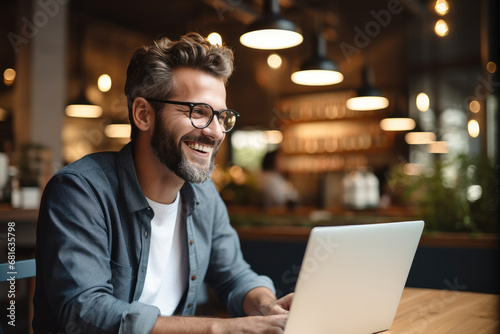 A business owner looking at a laptop and smiling, Happiness.