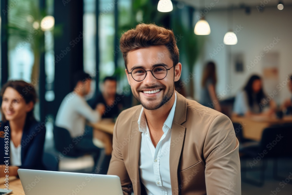Happy young man dressed in business casual working in a bright startup office with her colleagues working in the background. Happy young man dressed in business casual working in a bright startup office with her colleagues working in the background.
