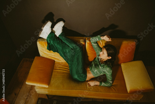 Photography Young non-binary Asian person in fashionable green outfit posing on yellow couch