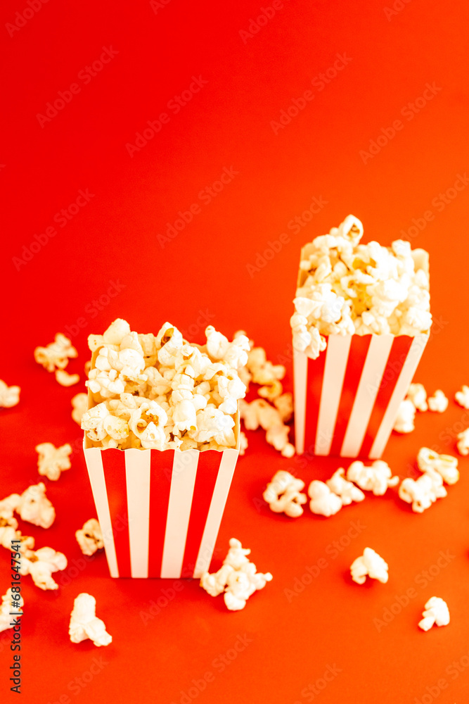 Red and white striped boxes with popcorn on a red background. Entertainment concept. Movie night with popcorn. Cinema theme.