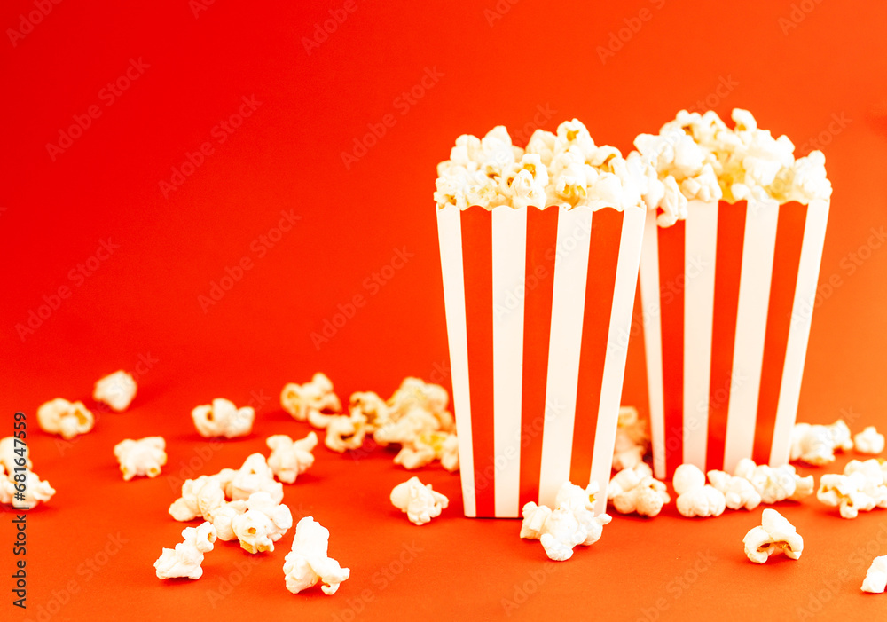 Red and white striped boxes with popcorn on a red background. Entertainment concept. Movie night with popcorn. Cinema theme.