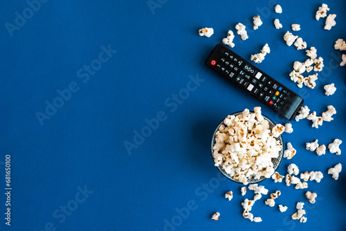 Popcorn and decorative pumpkins with TV remote on a blue background with copy space. Movie night concept. Wateching TV themed photo. Fall or autumn TV shows.