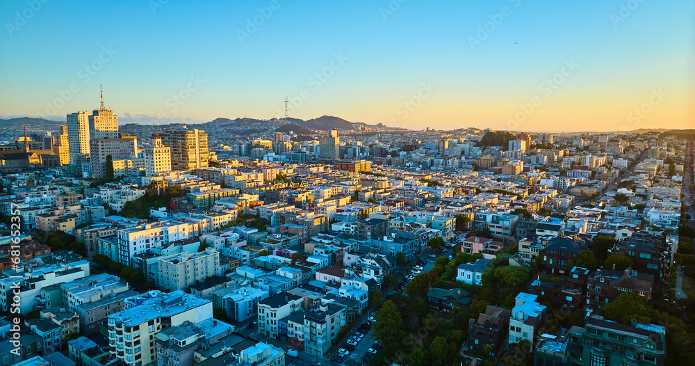 Sunset San Francisco aerial residential area with shadows over buildings and golden light on skyscrapers, CA