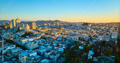 Sunset San Francisco aerial residential area with shadows over buildings and golden light on skyscrapers, CA