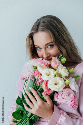 Portrait of a beautiful delicate woman in a pink dress with a bouquet of flowers