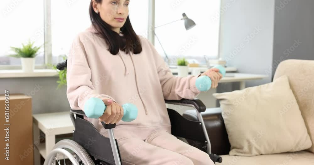 Young woman doing hand exercises while sitting in wheelchair. Physical exercise for people with disabilities concept Young woman doing hand exercises while sitting in wheelchair. Physical exercise for people with disabilities concept