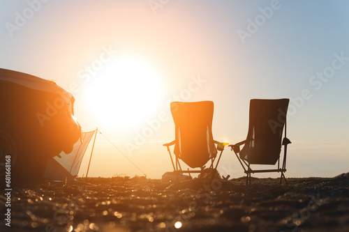 Two empty picnic chairs, next to a car, outdoors. place for camping and weekend getaway photo