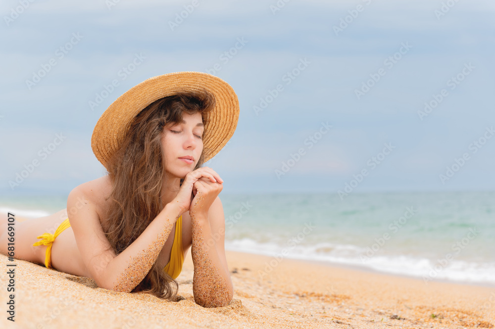 Summer lifestyle. Portrait of a beautiful girl with a slim body in a bikini enjoying life and lying with her eyes closed on the sand on the beach of a tropical island. Vacation