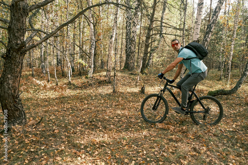 An active lifestyle.Cyclist with a backpack on a mountain bike in the autumn forest