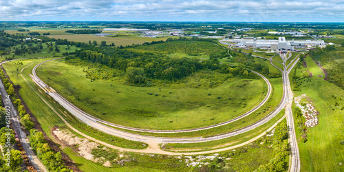 Fototapeta Naklejka Na Ścianę i Meble -  Panorama railroad tracks Progress Rail Services aerial with lush grass and trees, sunny summer day