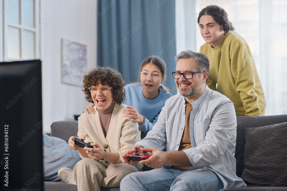 Family of four having fun together at home while sitting on sofa in the living room Family of four having fun together at home while sitting on sofa in the living room