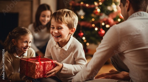 little boy opening pile of presents and smiling with excitement while his family looks on in delight