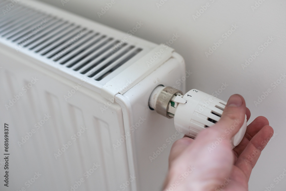 Man's hand holding the regulation knob of domestic heating system Man's hand holding the regulation knob of domestic heating system