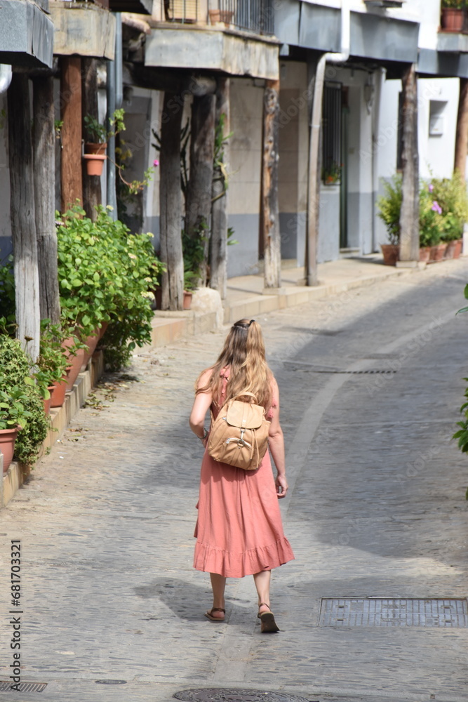 a girl with a dress and a backpack sightseeing in a village