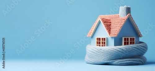 Home in a knitted scarf on a blue background, Concept of the heating system in a winterized house