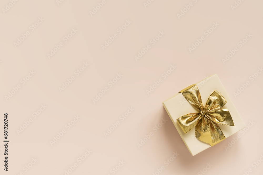 gift box with gold bow on peach background. top view, space for text gift box with gold bow on peach background. top view, space for text