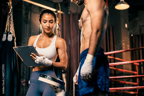 Muay Thai boxer step on weight scale for boxing class designation by weight measurement before boxing fight match. Dedicated athlete fitness and physical boxer\'s body readiness. Impetus
