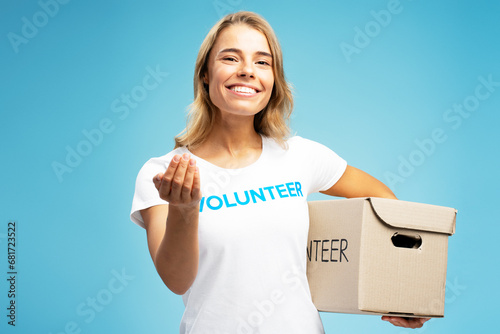 Smiling volunteer holding donation box isolated on blue background. Charity center 