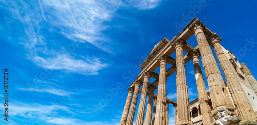 View from below of the Roman Temple of Diana with well preserved Corinthian style marble columns with a clear blue sky with white clouds shrouded in it. Meria, province of Badajoz, Extremadura, Spain. photo