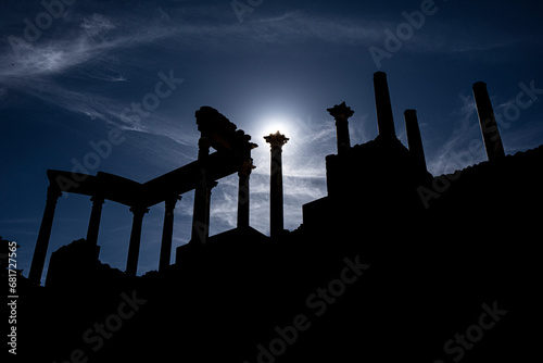 View from below of the capitals, cornice and columns of the Roman theater in Mérida, with the moonlight backlighting at sunset creating a divine glow on the column capital. photo