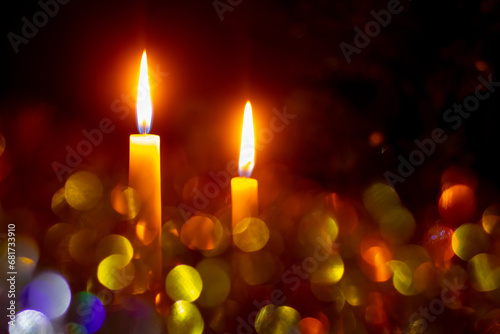 Two candles burning on a dark background with bokeh during Christmas and New Year celebrations