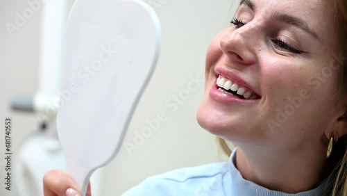 Happy woman looking at mirror enjoy healthy clean teeth beautiful smile after treatment at stomatology clinic. Pretty female patient and dentist doctor admiring result tooth whitening at dentistry 