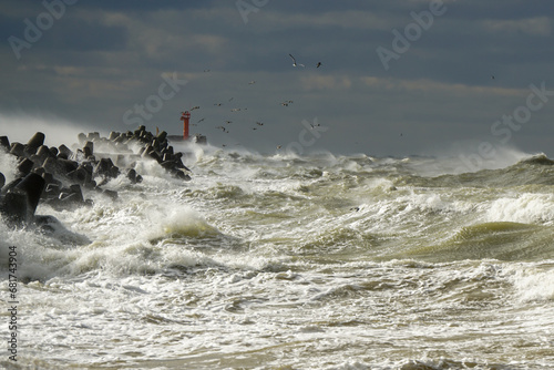 Storm at sea, high waves crashing against the concrete breakwaters of the port, white splashes