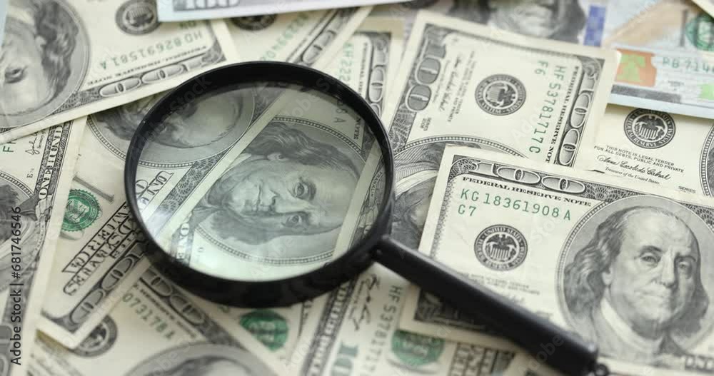 Magnifying glass lying on lot of paper dollar bills closeup 4k movie slow motion. Counterfeiting concept Magnifying glass lying on lot of paper dollar bills closeup 4k movie slow motion. Counterfeiting concept
