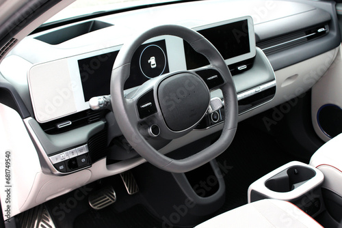 Electric car interior details. Inside car interior with steering wheel and dashboard, front seats, driver and passenger, textile, windows, door panels, console. Luxury car Interior. © Best Auto Photo