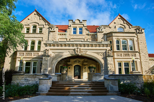 Entrance Minnetrista Museum and Gardens mansion building under cloudy blue sky on summer day