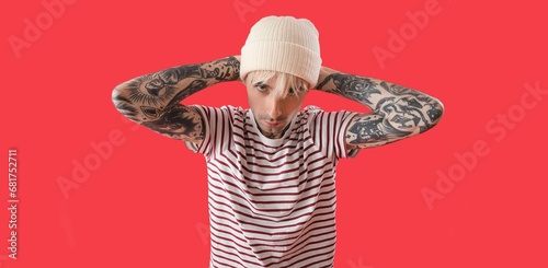 Cool tattooed young man on red background