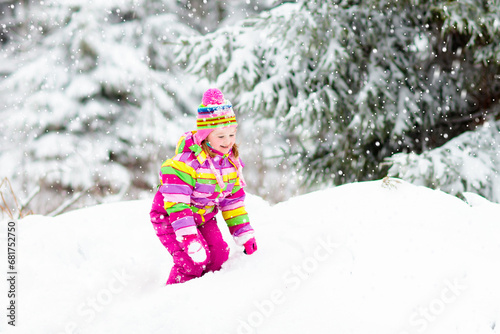Child playing with snow in winter. Kids outdoors.