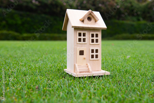 Building, apartment, construction and architecture business. Wooden toy house on grass.