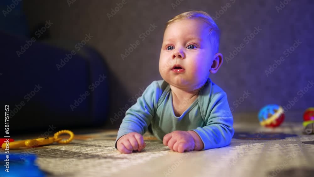 Lovely big-eyed baby looking ahead with surprise. Beautiful infant lies on the floor close up. Lovely big-eyed baby looking ahead with surprise. Beautiful infant lies on the floor close up.
