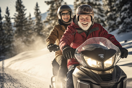 Pareja de hombre y mujer de la tercera edad, divirtiendose montados en una moto de nieve bajando poruna montaña nevada en invierno photo