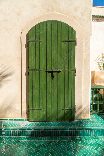 Green wooden door, to the secret garden of the city of Marrakech, on a sunny day