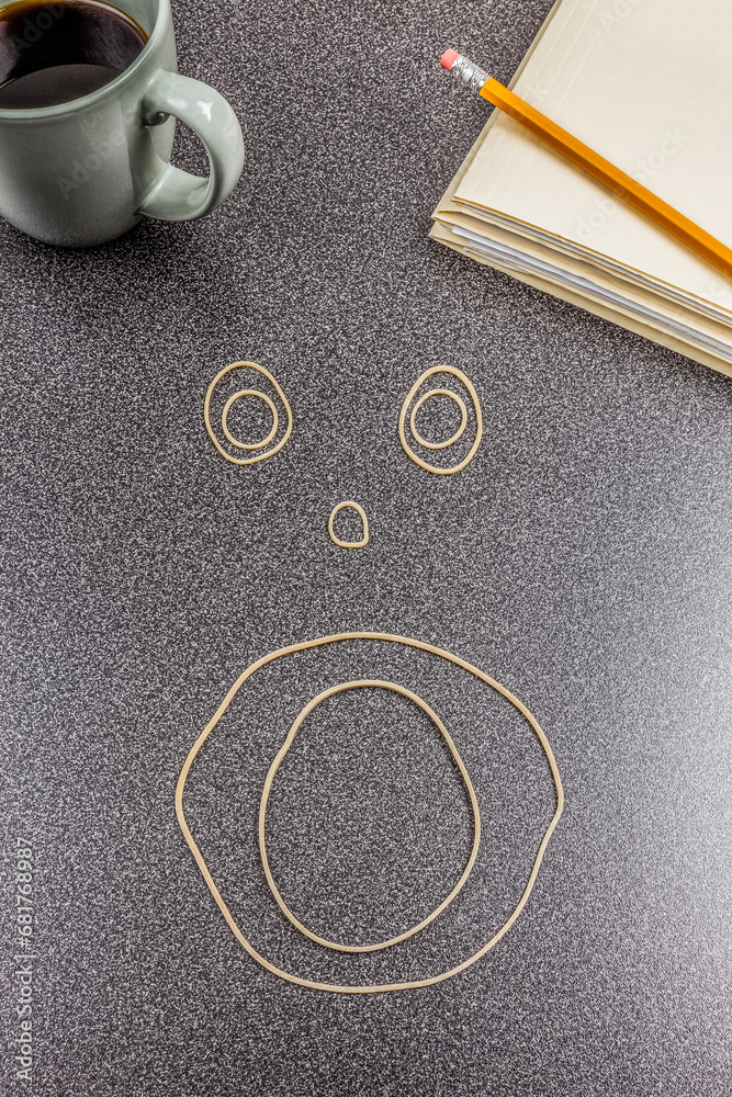 Face made out of rubber bands on office desk