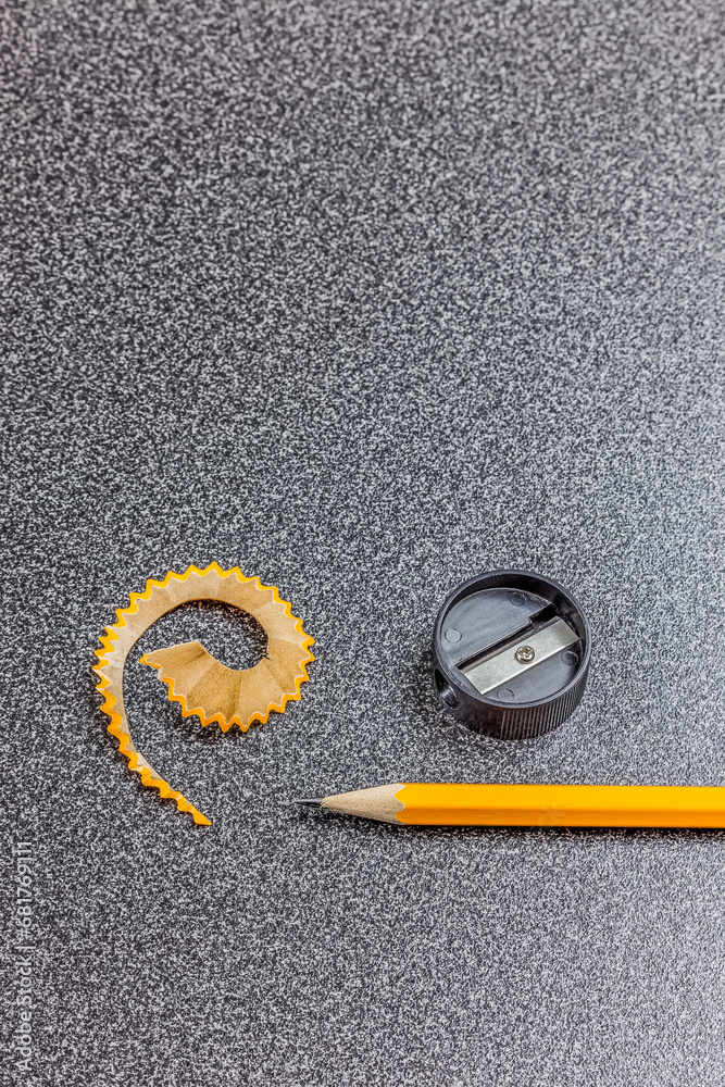 Pencil, pencil sharpener and pencil shaving on desk, close-up