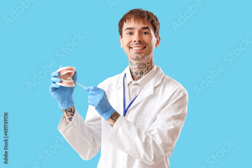 Male dentist with jaw model...