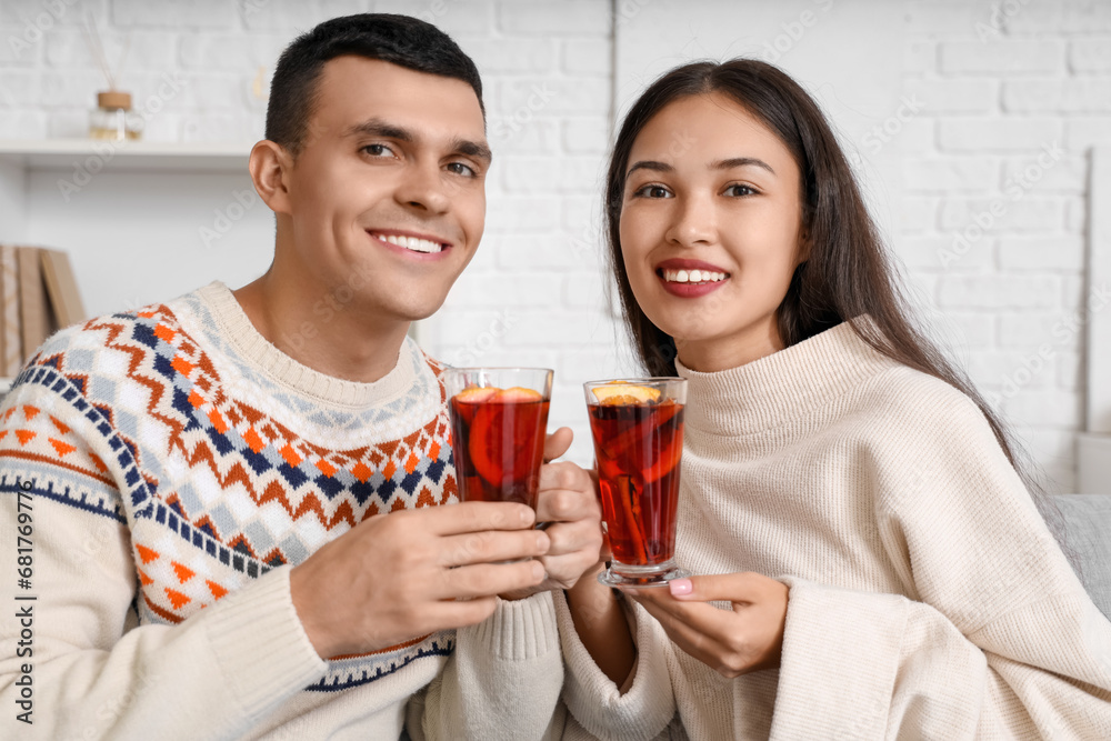Happy couple with glasses of warm mulled wine in living room, closeup Happy couple with glasses of warm mulled wine in living room, closeup