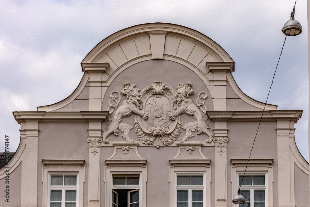 Elements of facade of house with bas-reliefs of lion figures, old coats of arms in Landshut, Bavaria, Germany.