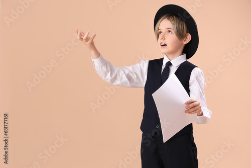 Little actor with film script on beige background