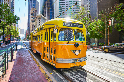 Yellow Fishermans Wharf streetcar trolley for F Market with skyscraper buildings San Francisco, CA