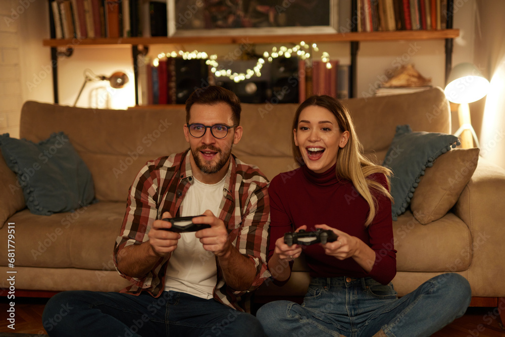 Obraz premium Young couple having fun at home playing video games